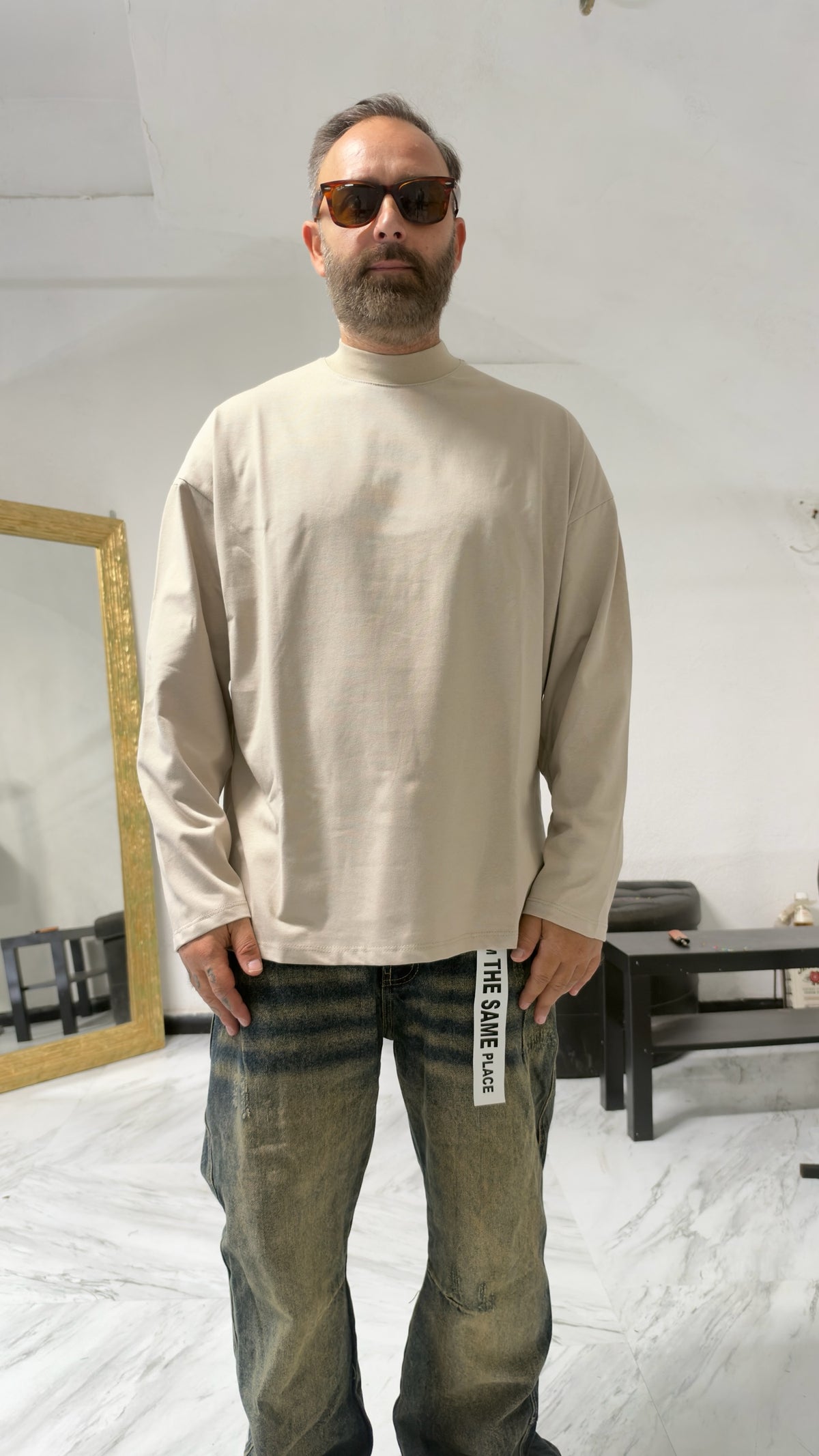 Uomo indossa maglia a maniche lunghe MOMAREVENGE color beige con collo alto e vestibilità oversize in cotone