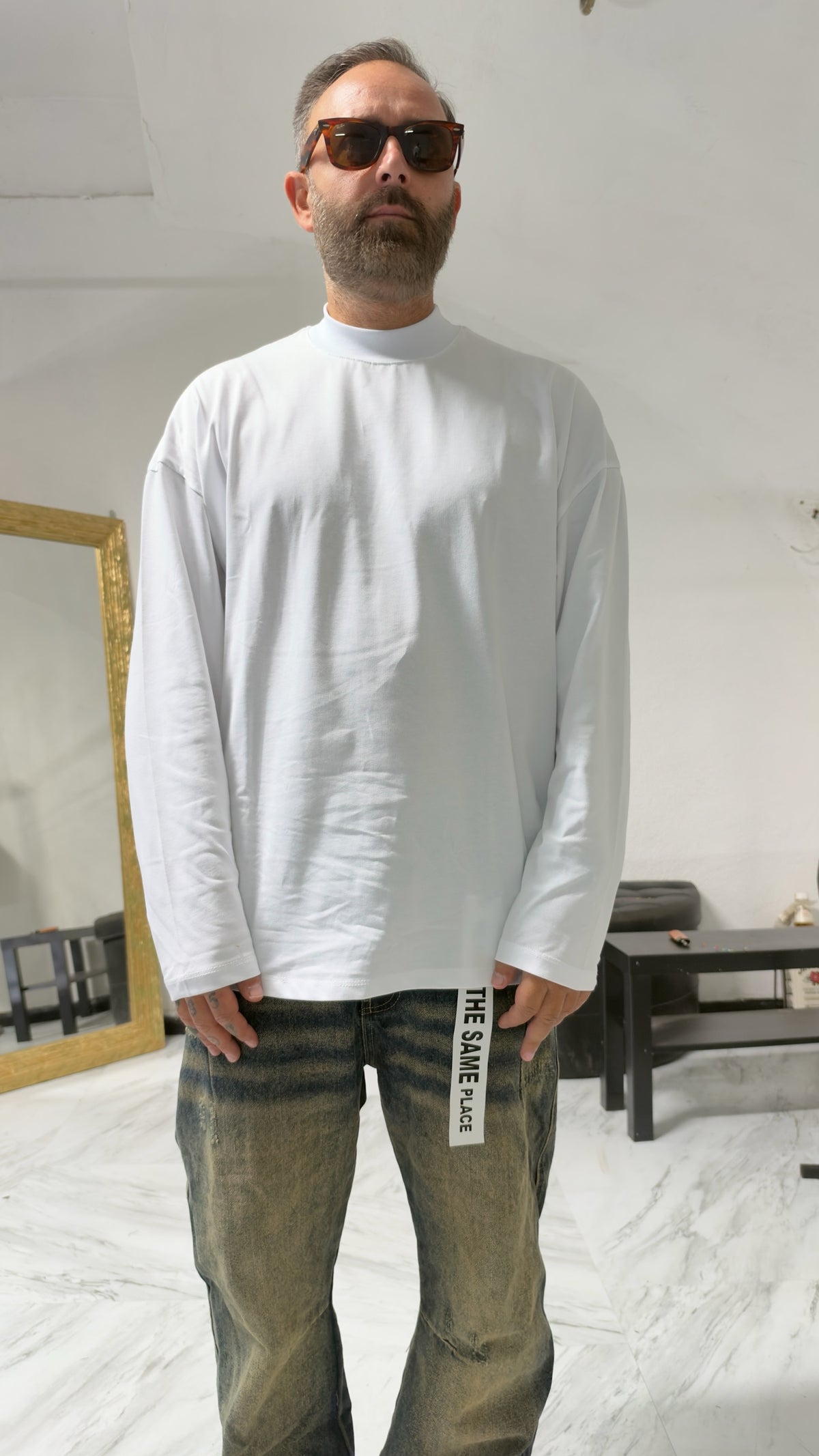 Modello indossa maglia a maniche lunghe bianca MOMAREVENGE con collo alto e vestibilità oversize in cotone