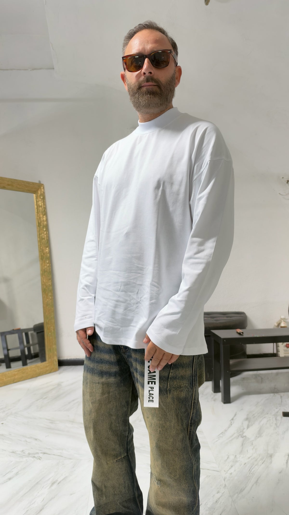 Uomo indossa una maglia MOMAREVENGE a maniche lunghe bianca con collo alto, vestibilità oversize e stile minimalista.