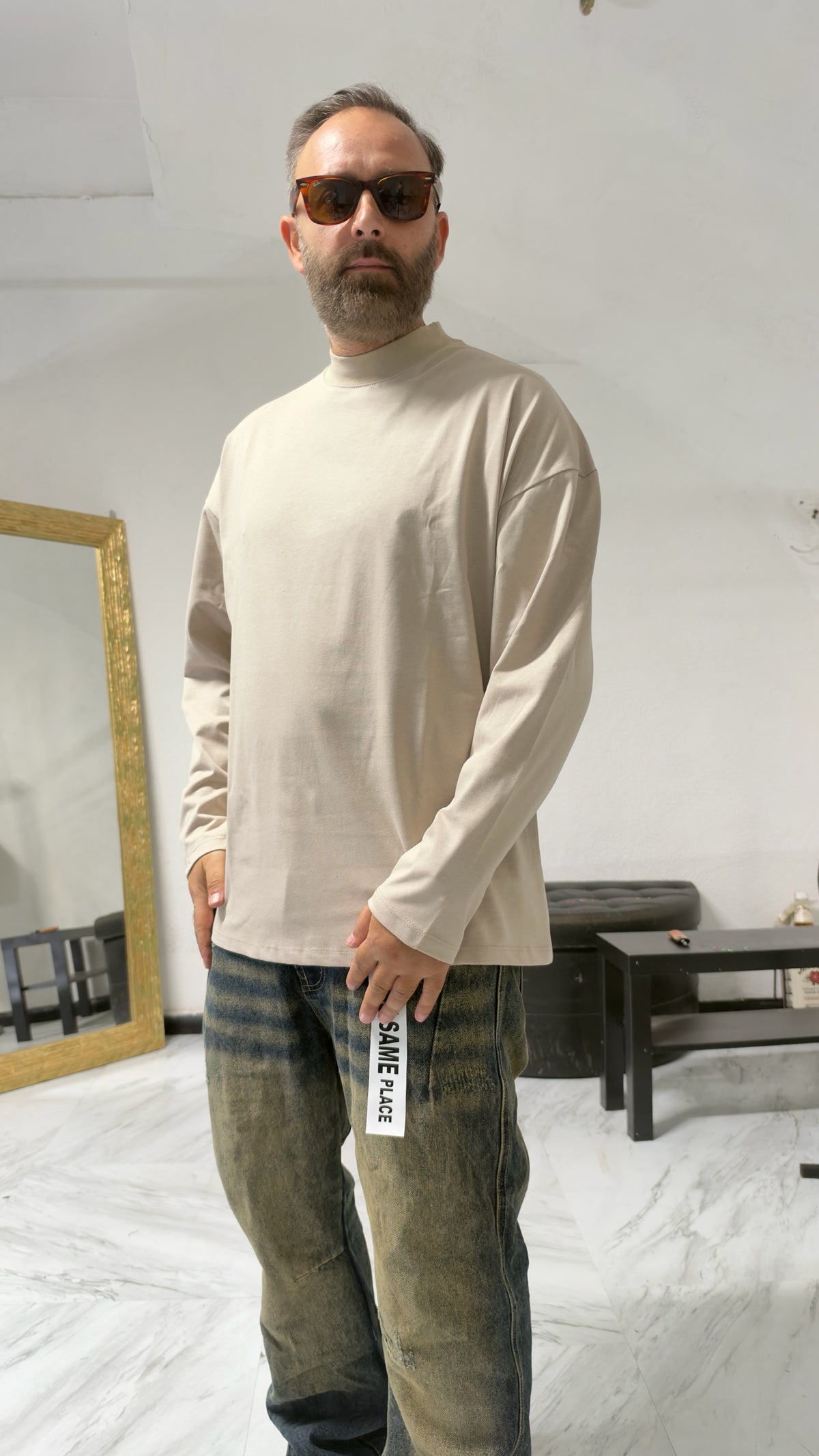 Uomo indossa maglia a maniche lunghe MOMAREVENGE color beige con collo alto e vestibilità oversize in cotone