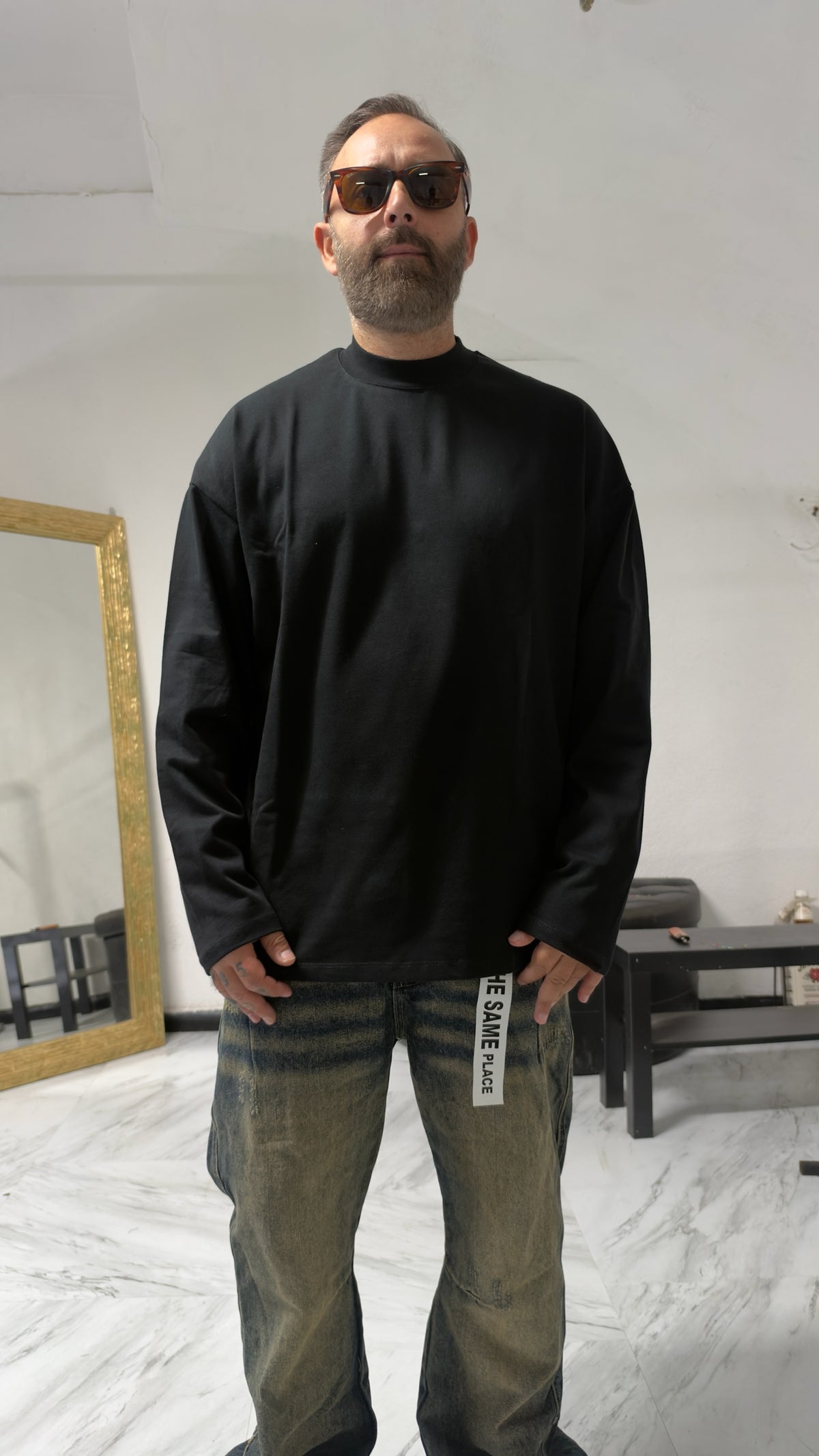Uomo con occhiali da sole indossa una maglia a maniche lunghe MOMAREVENGE nera a collo alto dal taglio oversize